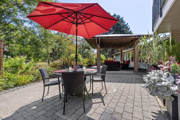 Outdoor seating area with a red umbrella and plants