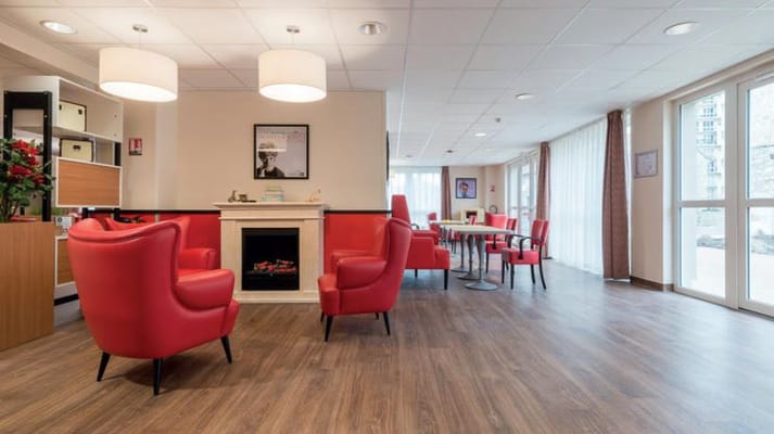 Bright common area with red chairs and a fireplace