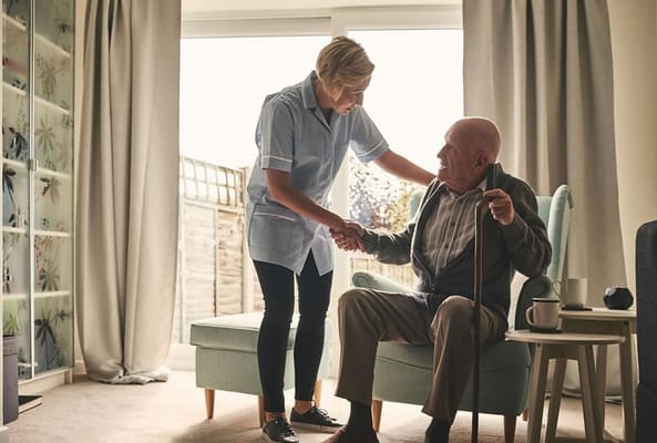 Caregiver assisting an elderly man in a cozy interior