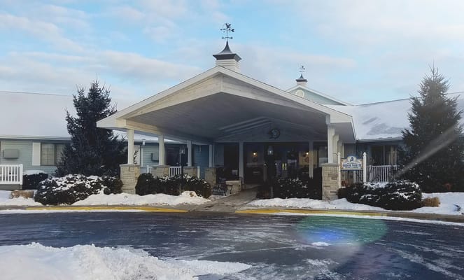 Front entrance of a senior living facility with snowy landscape