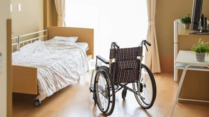 Interior of a senior living room with a bed and a wheelchair