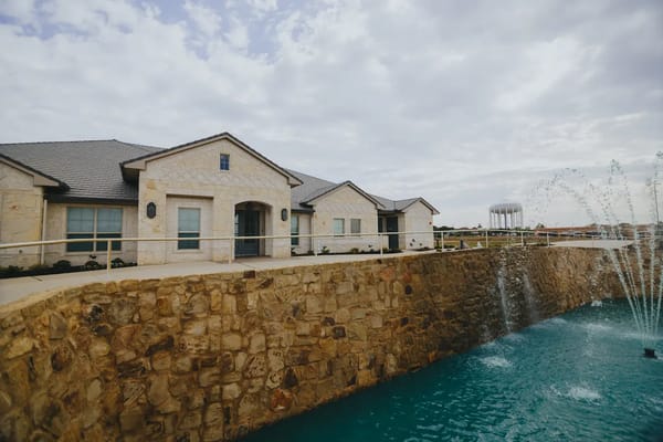 Exterior of Avalon Memory Care featuring a stone wall and fountain