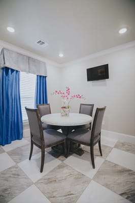 Round dining table with gray chairs and blue curtains in a bright room