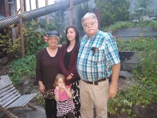 Four family members posing outdoors in a garden area.