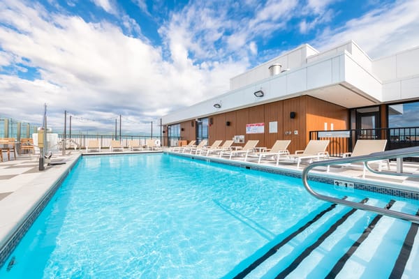 Rooftop pool area with lounge chairs and beautiful sky