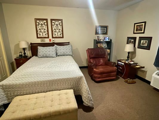 A cozy bedroom with a bed, armchair, and decorative wall art.