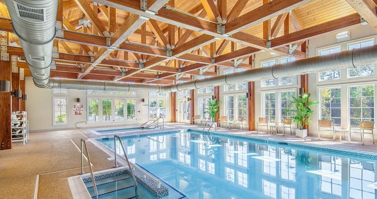 Indoor swimming pool with large windows and wooden beams