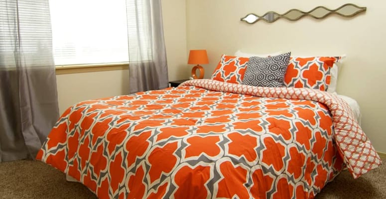 Bright bedroom with orange and gray bedding