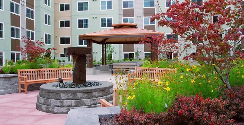 A serene courtyard featuring a gazebo, benches, and vibrant flowers at Celebration Senior Living.