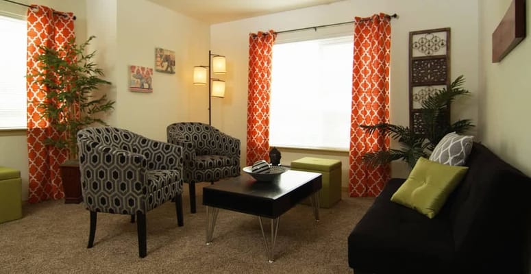 A comfortable living room featuring patterned chairs and colorful curtains.