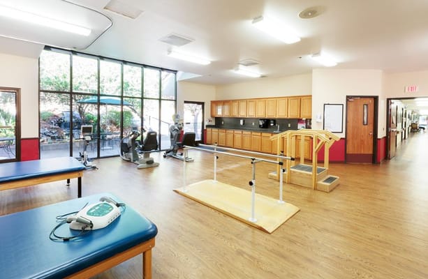A spacious rehabilitation area with exercise equipment and natural light
