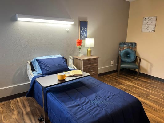 A well-decorated resident room with a bed and chair