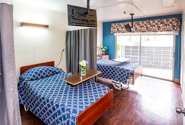 A cozy resident room with two beds and a TV