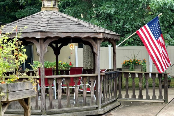 A gazebo in a garden with an American flag