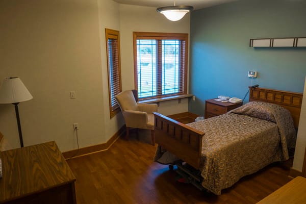 A cozy bedroom with a bed, chair, and window at Eden Meadows.