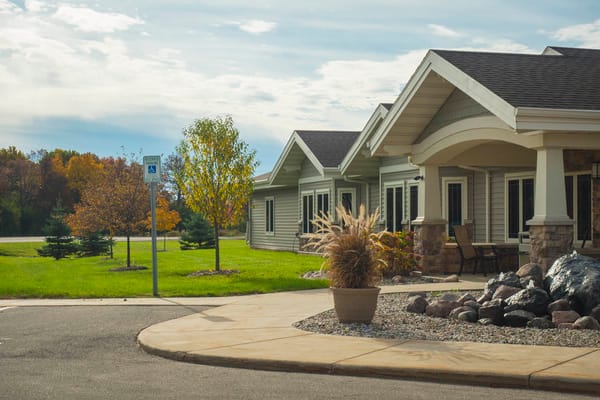 Exterior view of Eden Meadows senior living facility with trees and seating area.