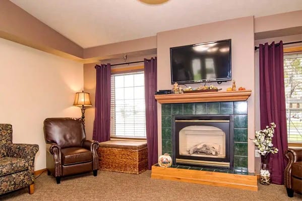 A cozy living room with a fireplace, armchairs, and decorative elements.