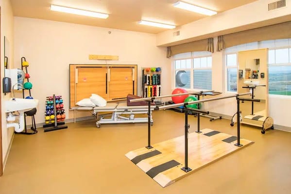 Interior view of a physical therapy room equipped with exercise equipment.