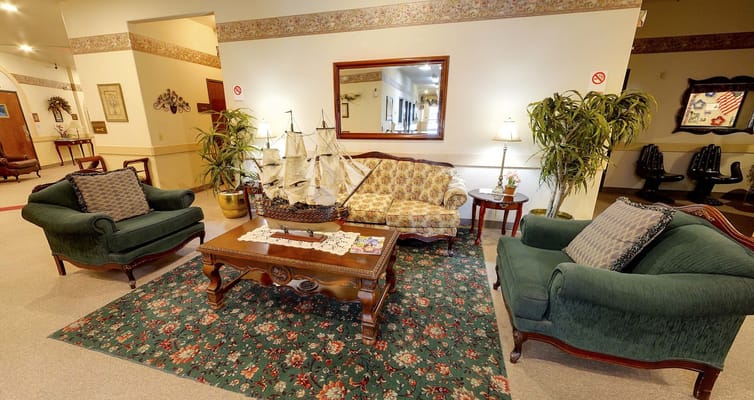 Cozy lounge with green sofas, floral couch, and a decorative ship model.