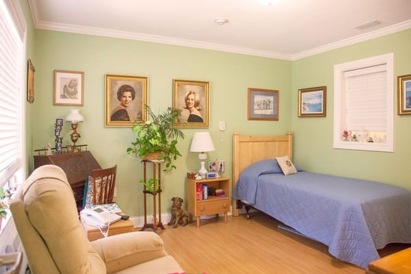 Interior view of a cozy resident room with green walls and framed portraits