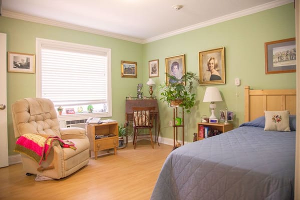 A comfortable bedroom with a bed, armchair, and decorative plants.