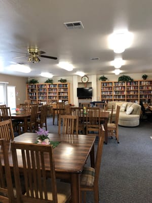 Lounge with wooden tables and bookshelves in Harmony Bay Apartments