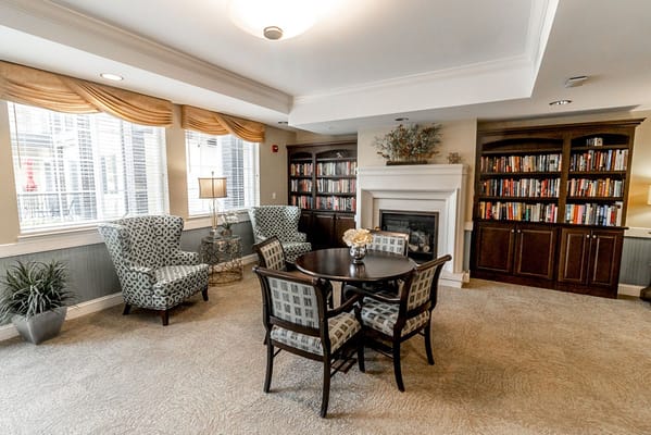 A cozy living room setting with chairs, a round table, and a bookshelf.