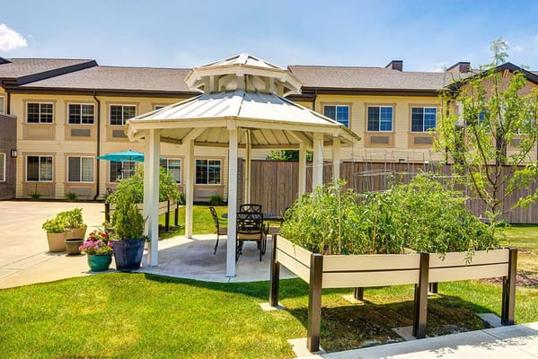 A gazebo in a landscaped backyard with raised garden beds.