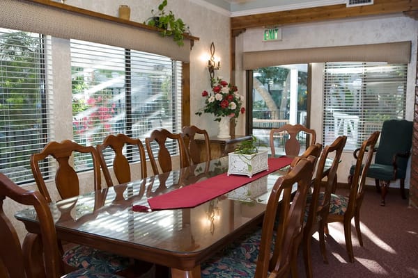 Wooden dining table with chairs and floral decorations in a well-lit room