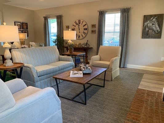 Cozy living room with striped sofa, accent chairs, and decorative clock