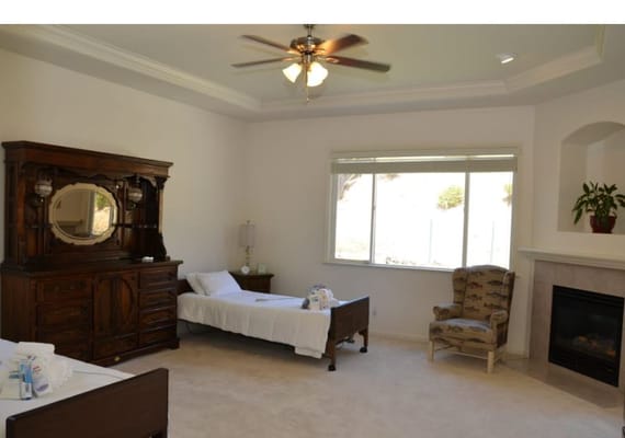 A cozy bedroom with a single bed, dresser, and armchair.