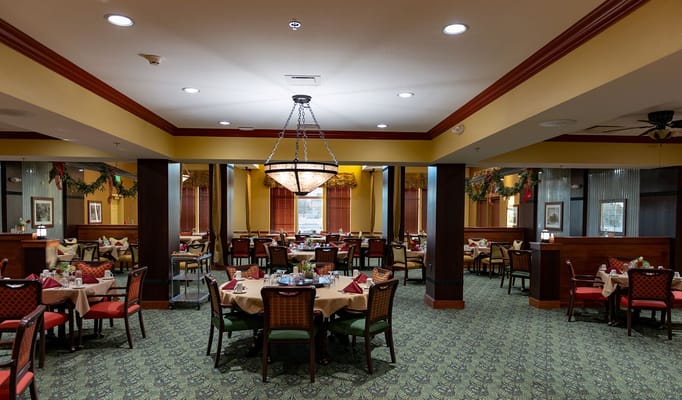 Spacious dining room with elegantly set tables and festive decorations.