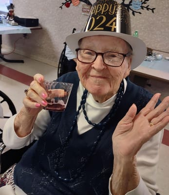 Senior resident celebrating with a drink and festive hat