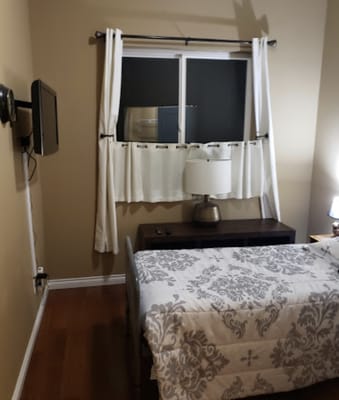 A neatly arranged bedroom featuring a bed, lamp, and window