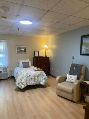 A cozy resident room with a bed and chair