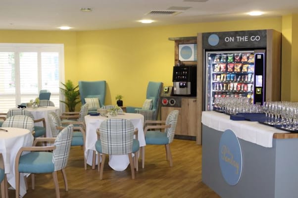 Cozy lounge area with tables and a vending machine at McCoy's Personal Care Home