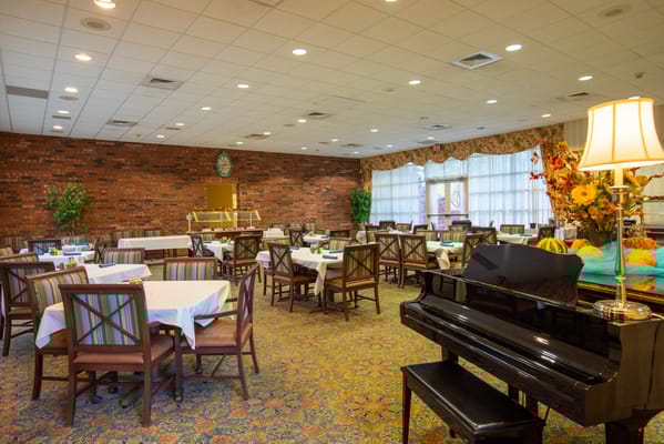 Dining area with tables and piano in a retirement community