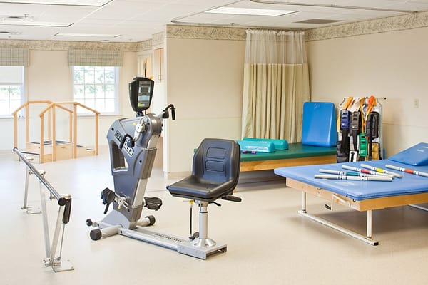 A rehabilitation room with exercise equipment and therapy mats.
