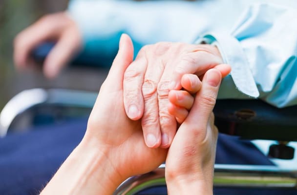 A caregiver holding the hand of a senior resident