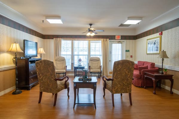 Lounge area with seating, coffee table, and TV in senior living facility