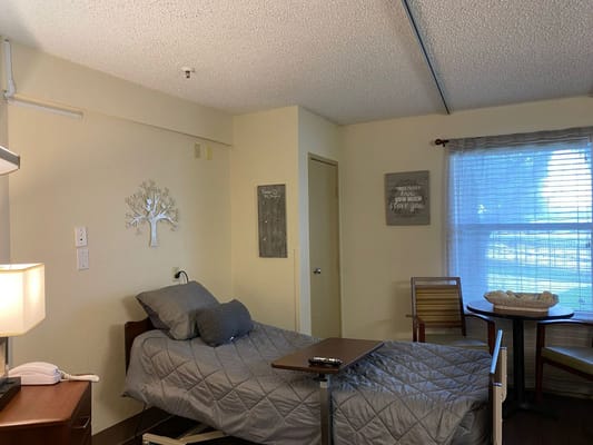 Simple interior view of a resident's room with a bed and chair