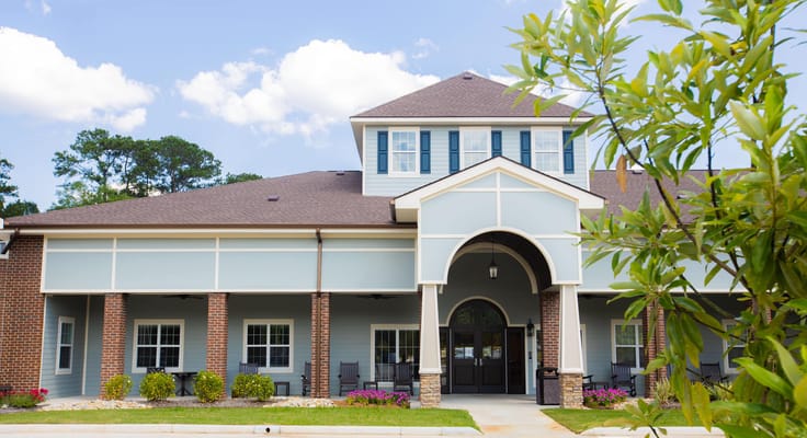 View of the front entrance of Old Brownlee Community Care Center with seating area and landscaping
