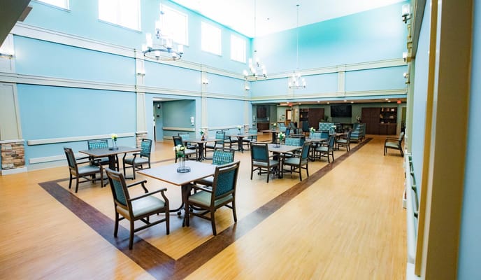 Bright, spacious common area with tables and chairs in Old Brownlee Community Care Center