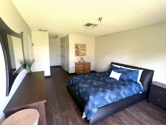 A cozy bedroom featuring a queen-sized bed and wooden furniture