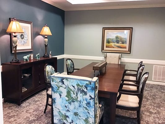 A dining room with a wooden table and colorful chairs in Orchard Park of Kyle.