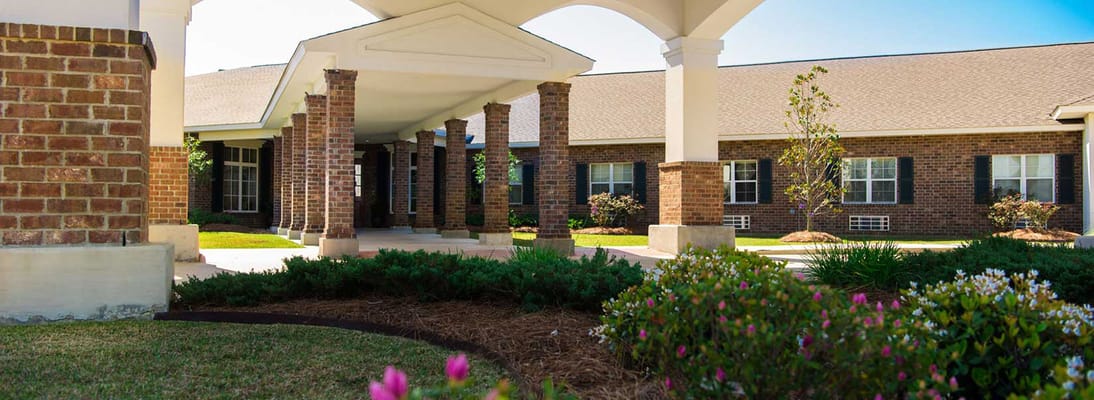 Entrance featuring brick columns and landscaped gardens at Ouachita Healthcare Rehabilitation Center.