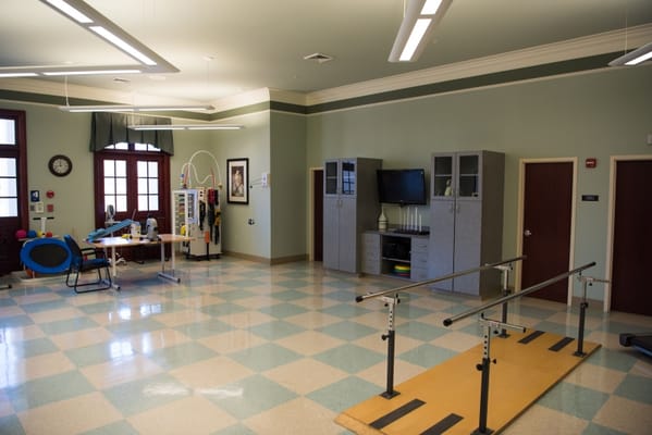 Spacious therapy room with exercise equipment and parallel bars