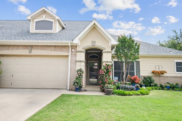 View of the front entrance with colorful flowers and a well-manicured lawn.