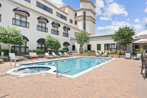 Outdoor pool with lounge chairs at Parc Place senior living facility.