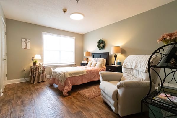 Cozy bedroom setup with a bed, chair, and natural light.